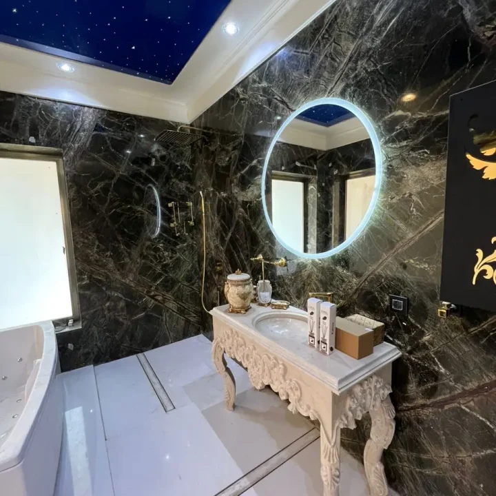 دیوارپوش سنگ تیره رگه‌دار، کف روشن و روشویی کلاسیک در حمام پروژه تنکابن